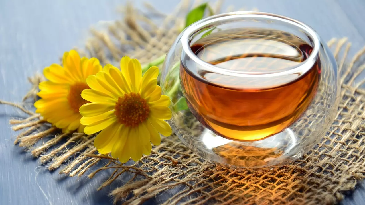 A steaming cup of chamomile tea on a wooden table.