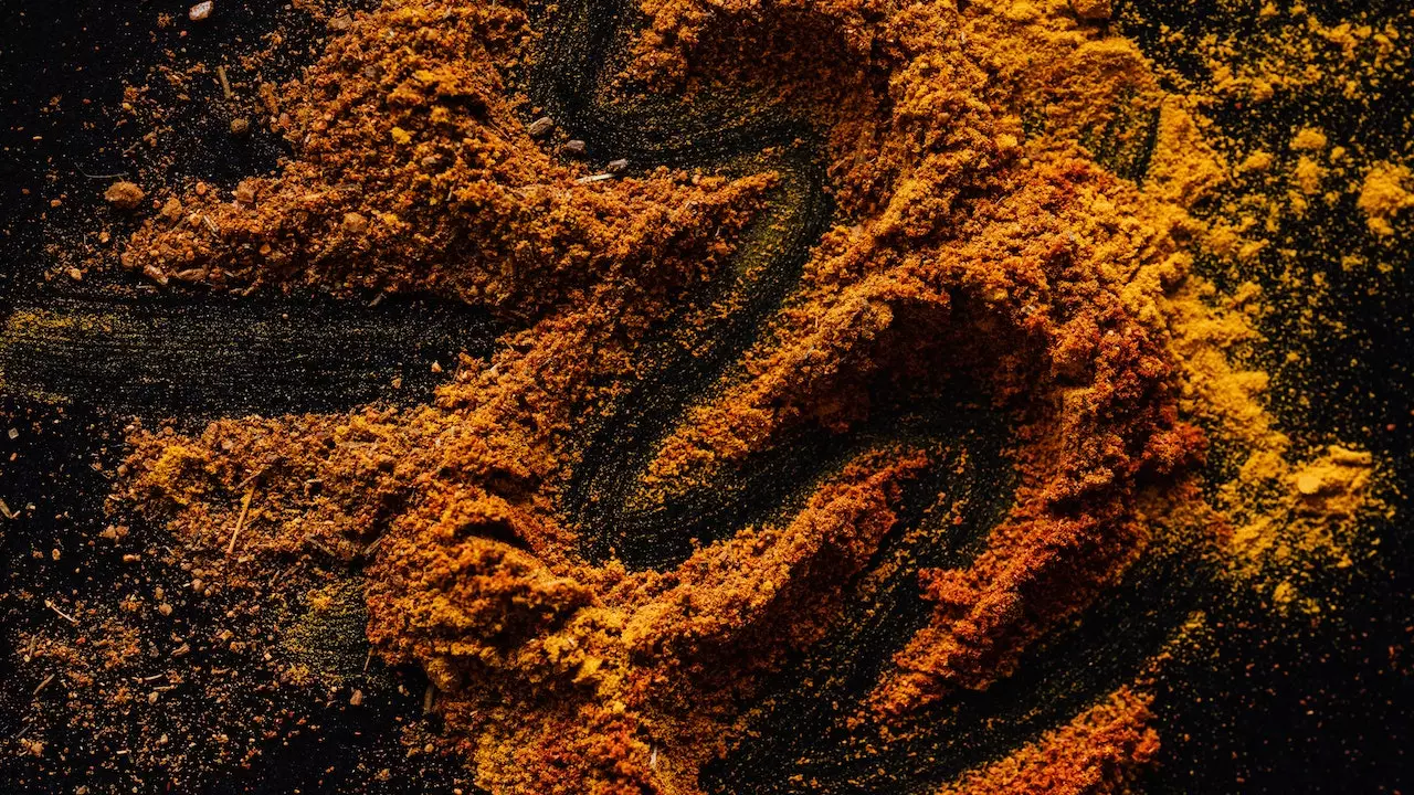 Turmeric powder and root on a wooden background.