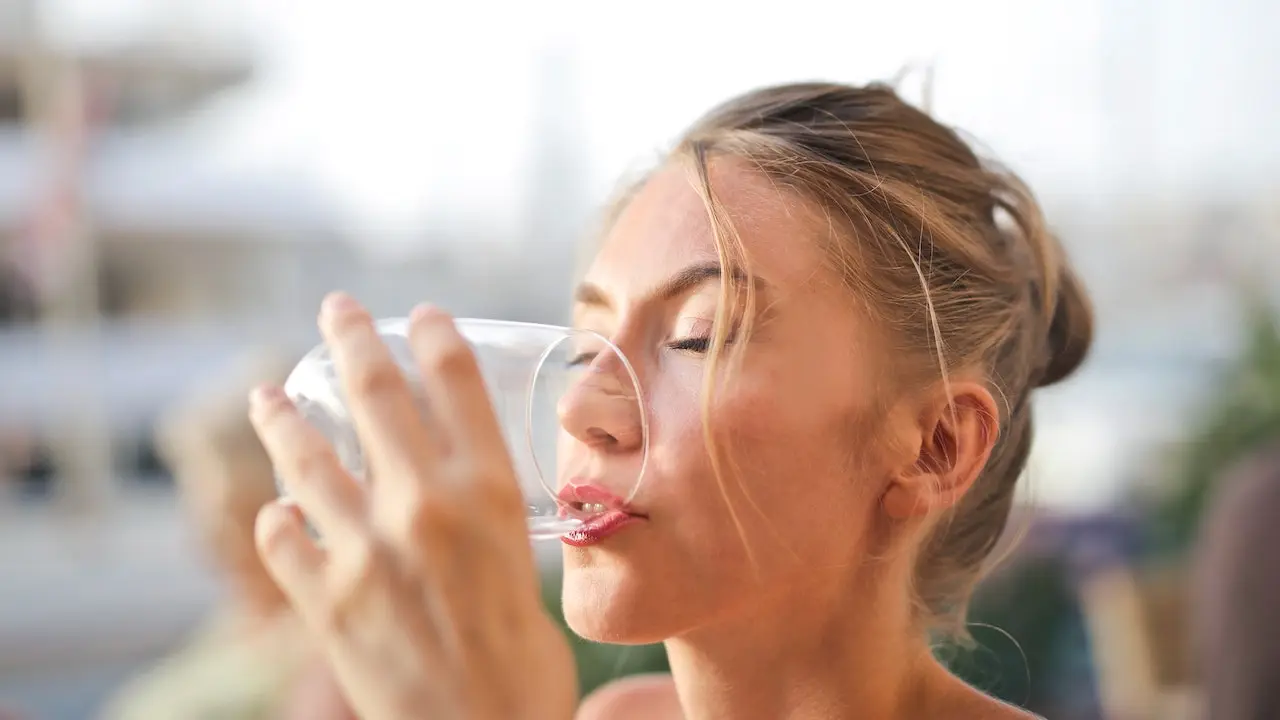 Glass of water with lemon slices and a checklist of skin-friendly foods