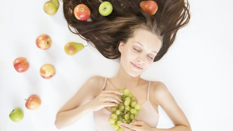 Woman with radiant skin holding a plate of assorted healthy foods