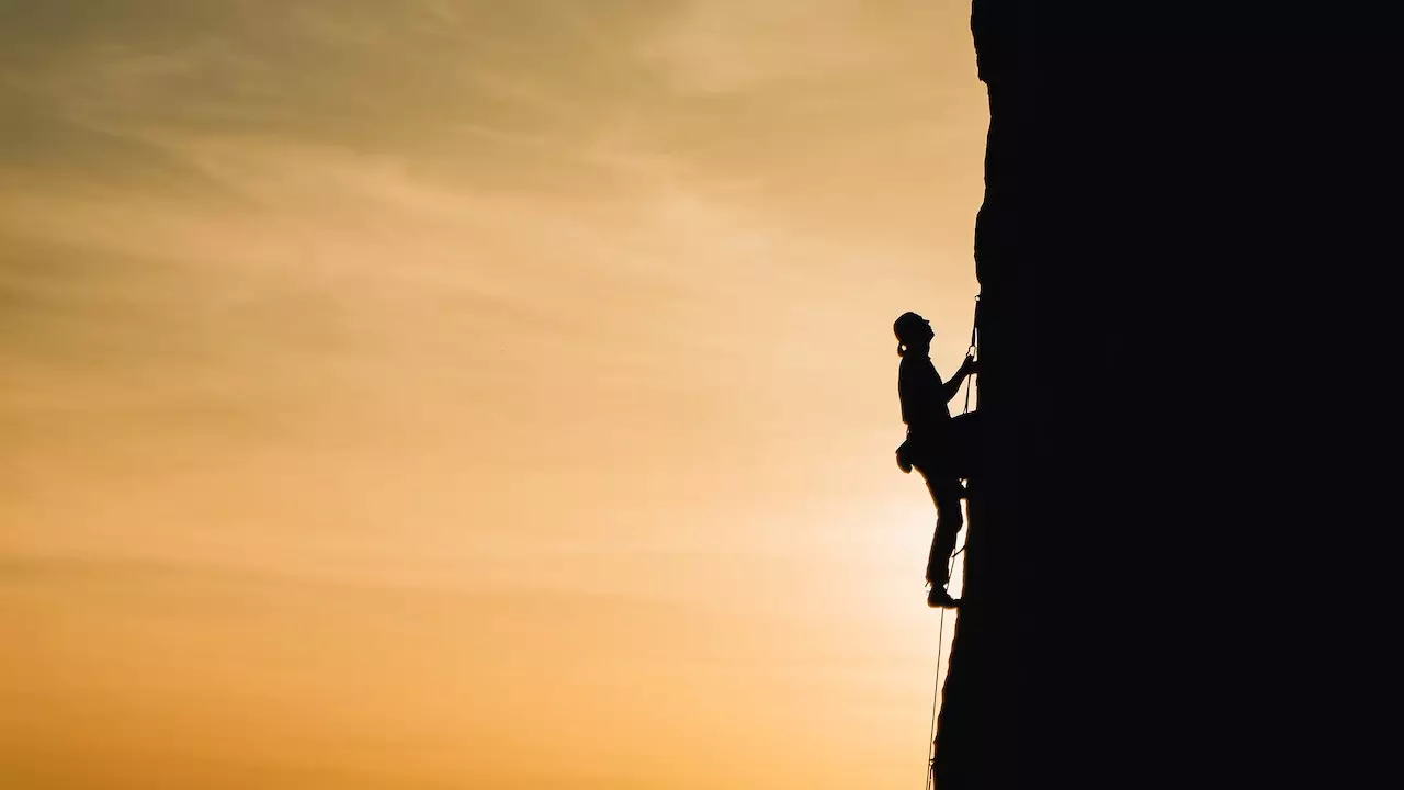 A person climbing a mountain peak, embodying the essence of confronting challenges head-on.